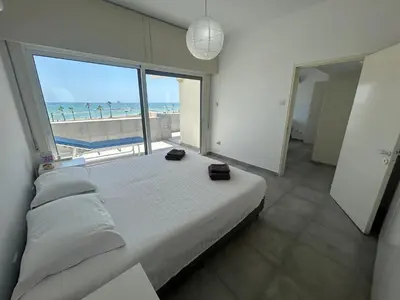 a bedroom with a large bed with a view of the beach at Julie's beach house in Voroklini