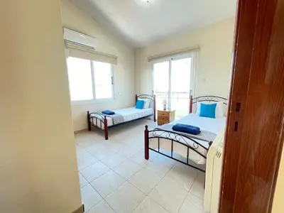 a bedroom with two beds and two windows at Sunset Pearl Holiday Villa in Ayia Napa