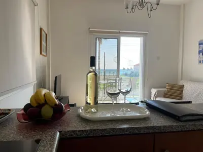 a bottle of wine and two glasses on a kitchen counter at Themis Beach Apartments in Larnaka