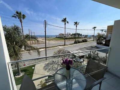 a balcony with a glass table and a view of the beach at Themis Beach Apartments in Larnaka
