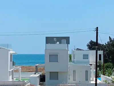 a white house with the ocean in the background at Ferienhaus_FamilyKrausz in Pervolia