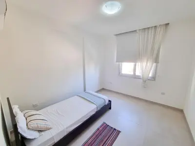 a white bedroom with a bed and a window at Seaside Elegance Retreat in Larnaka