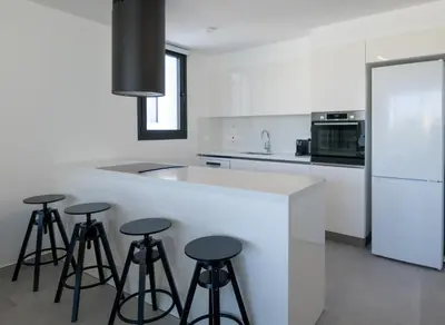 a kitchen with a white counter with stools around it at Phaedrus Living White Hills Suites Panoramic View in Aglantzia
