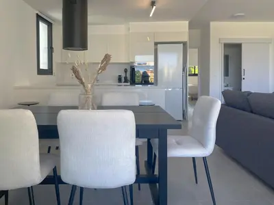 a dining room with a table and white chairs at Phaedrus Living White Hills Suites Panoramic View in Aglantzia