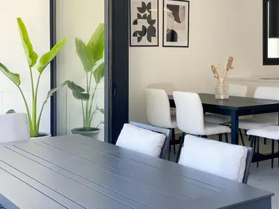 a dining room with a black table and white chairs at Phaedrus Living White Hills Suites Panoramic View in Aglantzia