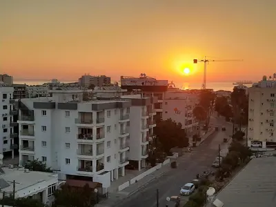 a sunset over a city with a white building at Happy Tucan in Larnaka