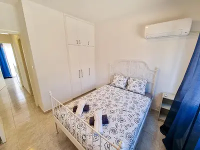 a bedroom with a bed with a blue and white comforter at Beach Vibes Beachfront Apartment in Pyla