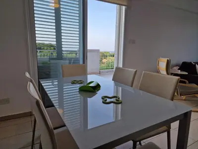 a dining room with a table and chairs and a window at Kalifi Pool Apartment in Paralimni