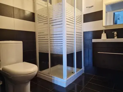 a bathroom with a toilet and a glass shower at Kalifi Pool Apartment in Paralimni