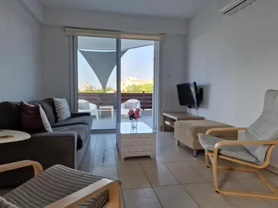a living room with a couch and chairs and a tv at Kalifi Pool Apartment in Paralimni
