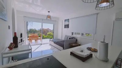 a white kitchen with a living room with a couch at STAY Monte Elias Apartment in Protaras