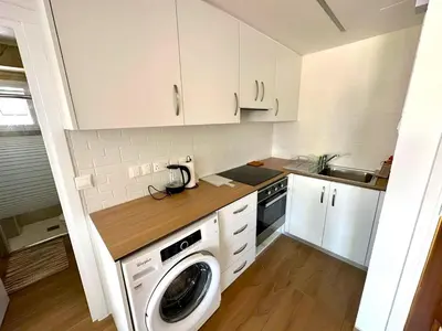 a kitchen with white cabinets and a washer at Sea View Apt - 2 min walk to the Beach & 200 Mbit Highspeed internet in Larnaka