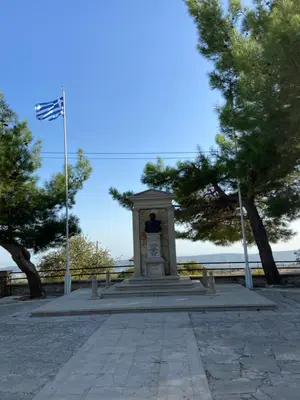 a statue in a park with trees and a flag at Lofitiko in Lofou