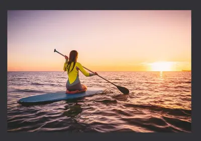 a woman is sitting on a paddle board in the water at Zima Two Seaside in Zygi