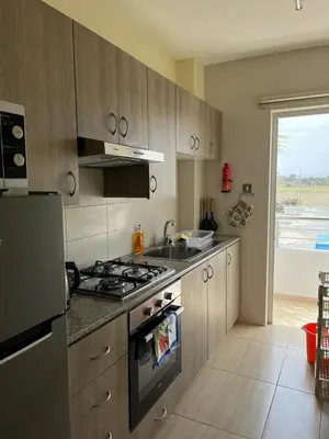 a kitchen with wooden cabinets and a stove top oven at Beach apartment Mackenzie, Larnaca in Larnaka