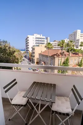 a bench and chairs on a balcony with a view of a city at Finikoudes 3 Bedroom Seaview Flat in Larnaka