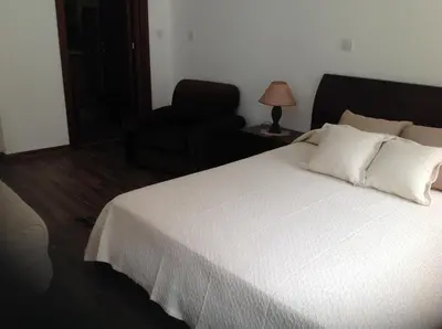 a bedroom with a white bed and a chair at Ta Spitakia tis Theodosias in Kalopanayiotis