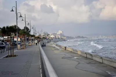 a sidewalk next to a beach with the ocean at Pelides Apartments in Larnaka