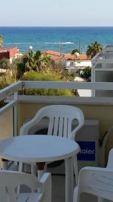 a white table and chairs on a balcony with the ocean at Pelides Apartments in Larnaka