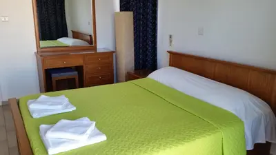 a bedroom with a green bed and a mirror at Pelides Apartments in Larnaka