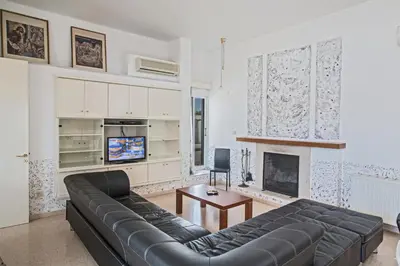 a living room with a black leather couch and a fireplace at Napa Nissi House in Ayia Napa