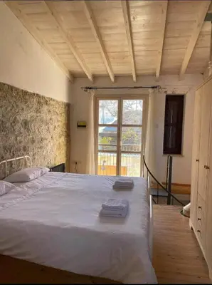 a bedroom with a large white bed with a window at Lofou Maisonette in Lofou