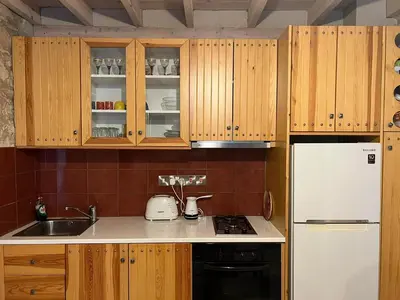 a kitchen with wooden cabinets and a white refrigerator at Lofou Maisonette in Lofou