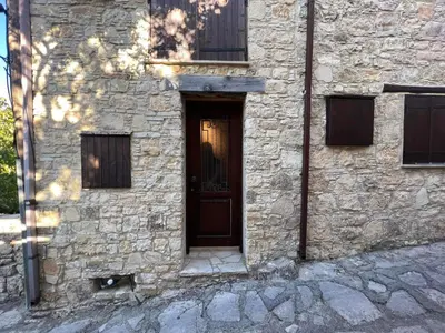 a stone building with a brown door and windows at Lofou Maisonette in Lofou