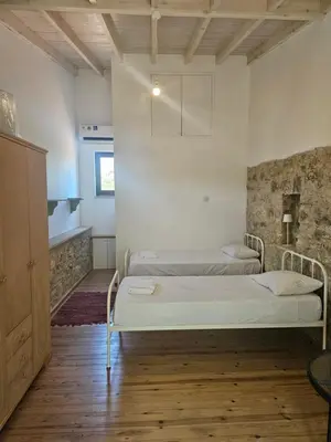 two beds in a room with white walls and wooden floors at Lofou Maisonette in Lofou