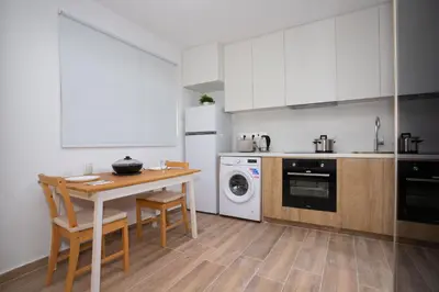 a kitchen with white cabinets and a table with chairs at STAY Zen Studio in Limassol