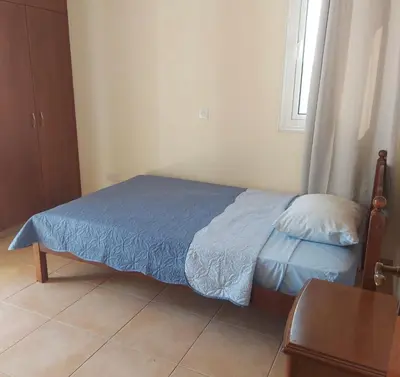 a bedroom with a bed with a blue blanket and a window at The T Villa in Protaras