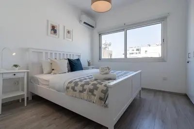 a white bedroom with a bed with a teddy bear on it at Hermes 2-Bedroom Apartment in Larnaca in Larnaka