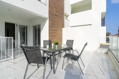 a glass table and chairs on a patio at Artemis 1-Bedroom Apartment in Larnaca in Larnaka