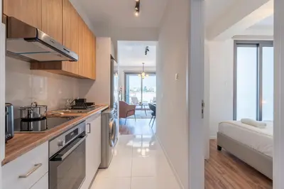 a kitchen with white cabinets and a couch in a room at Vanilla's Prime 1-Bedroom Apartment in Larnaca in Larnaka