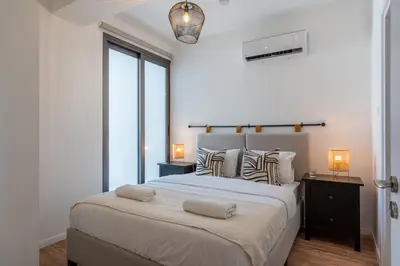 a white bedroom with a large bed with two lamps at Vanilla's Prime 1-Bedroom Apartment in Larnaca in Larnaka