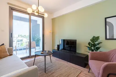 a living room with a tv and a couch and a table at Latte's Prime 1-Bedroom Apartment in Larnaca in Larnaka