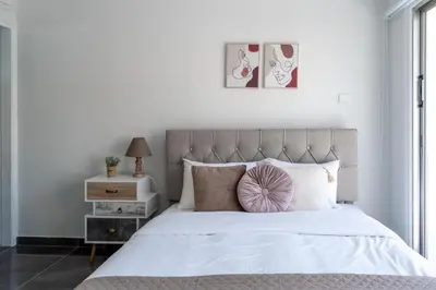 a bedroom with a white bed with a pink pillow at Powder’s 1-Bedroom Retreat in Mackenzy, Larnaca in Larnaka