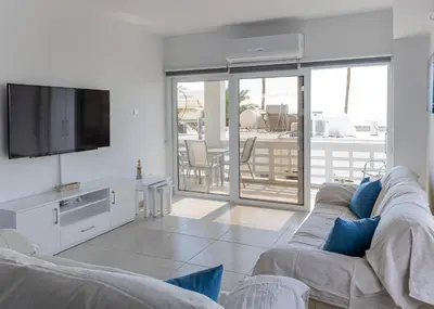 a living room with a couch and a flat screen tv at Larnaca BeachHouse in Larnaka