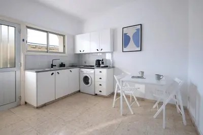 a white kitchen with a table and a washing machine at Urban Condo 10 - 2 Bdr in Nicosia