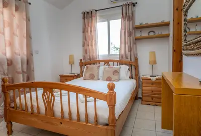 a bedroom with a wooden bed and a window at Sun & Sand Private Villa in Protaras