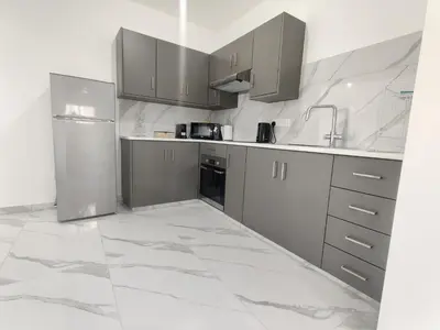 a kitchen with stainless steel appliances and marble floors at Maestro I Apartment in Larnaka