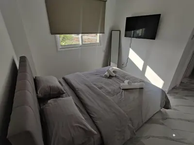 a bed in a bedroom with a couch and a tv at Maestro I Apartment in Larnaka