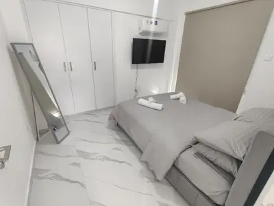 a white bedroom with a bed and a mirror at Maestro I Apartment in Larnaka