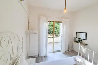 a white bedroom with a bed and a sliding glass door at Palmove Makenzie Studio 4 in Larnaka