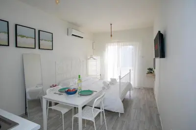a white dining room with a white table and chairs at Palmove Makenzie Studio 4 in Larnaka