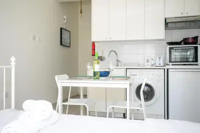 a kitchen with a table with wine glasses and a dishwasher at Palmove Makenzie Studio 4 in Larnaka