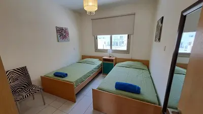 a small bedroom with two beds and a chair at Dream Beach House Steps from the Sea & Free Parking in Protaras