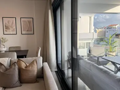 a living room with a couch and a large window at Phaedrus Living: White Hills Suites City View in Aglantzia