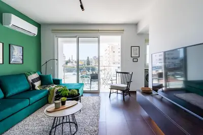 a living room with a green couch and a table at Harbor Apartments in Larnaca in Larnaka
