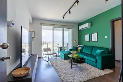 a living room with a green couch and a table at Harbor Apartments in Larnaca in Larnaka